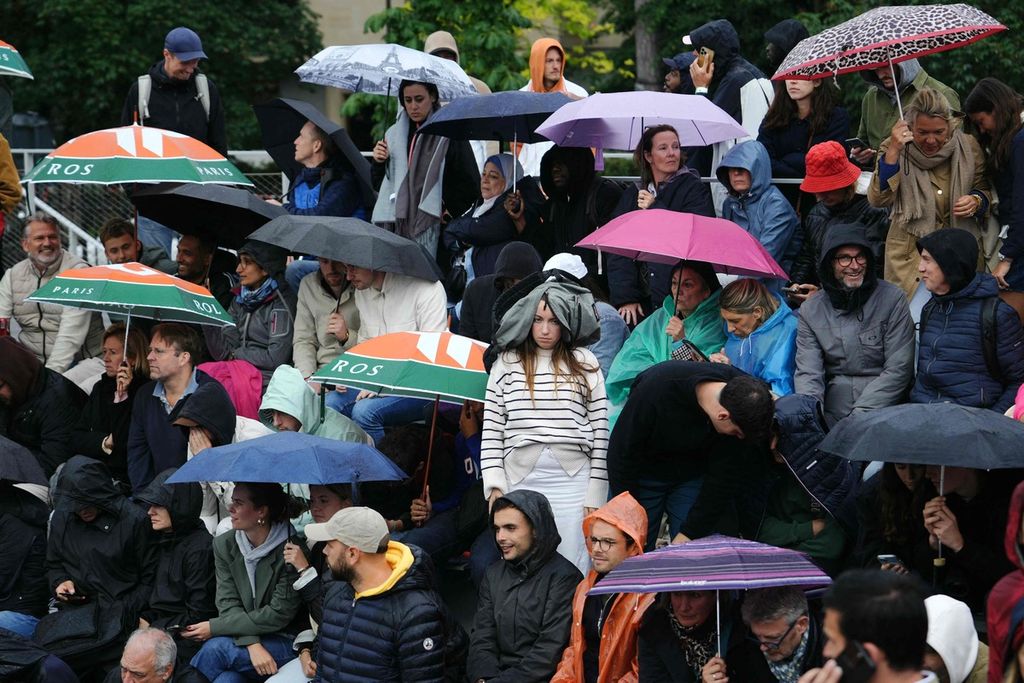 Penonton menyaksikan pertandingan turnamen tenis Grand Slam Perancis Terbuka saat hujan di Roland Garros, Paris, Jumat (31/5/2024). 