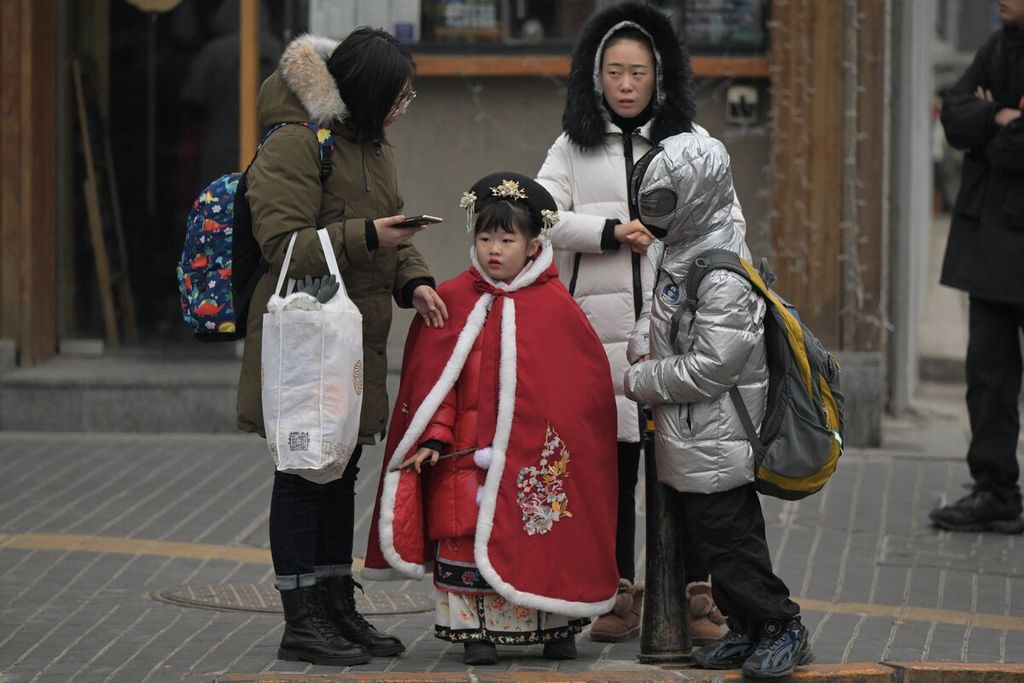 Bocah menunggu di pinggir jalan di Beijing, Rabu (17/1/2024). Populasi China kembali berkurang. 