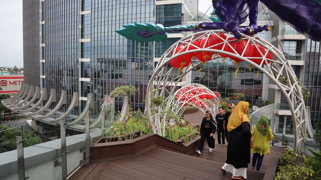 Pengunjung Pondok Indah Mall 3, Jakarta Selatan, menikmati pemandangan dari jembatan di atap gedung pusat perbelanjaan itu, Rabu (8/2/2023). Tempat bernama Love on Top itu bisa dikunjungi secara gratis.
