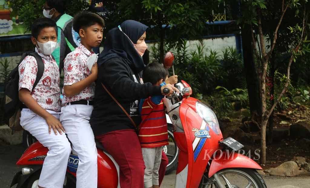 Seorang ibu membonceng anak-anaknya pulang dari sekolah dasar di Pondok Kelapa, Kecamatan Duren Sawit, Jakarta Timur, Kamis (3/2/2022). 