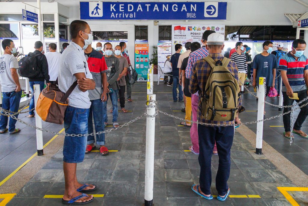 Pekerja migran Indonesia menunggu petugas untuk mengecek kesehatan dan dokumen imigrasi mereka di pintu kedatangan Pelabuhan Internasional Batam Centre, Kota Batam, Kepulauan Riau, Kamis (21/5/2020). 