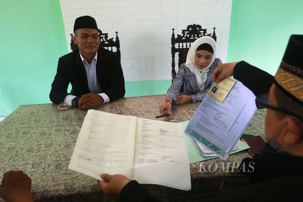 Penghulu merampungkan berkas administrasi setelah prosesi akad nikah pasangan di KUA Cakung, Jakarta Timur, Selasa (22/2/2022).
