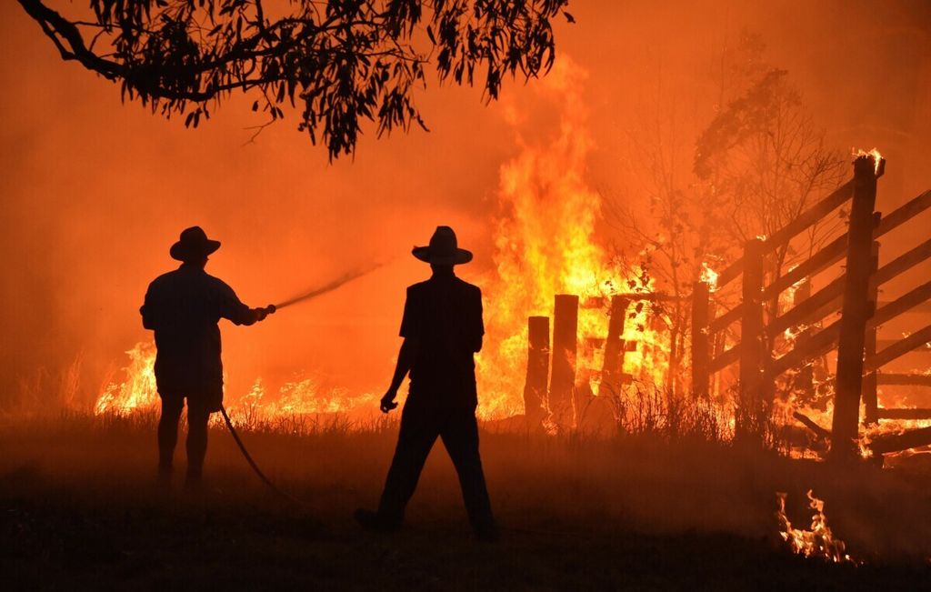 Warga Hillsvlile, tak jauh dari Taree yang berada sekitar 350 kilometer di utara Sydney, Australia berupaya memadamkan api yang membakar lahan mereka, pada 12 November 2019.