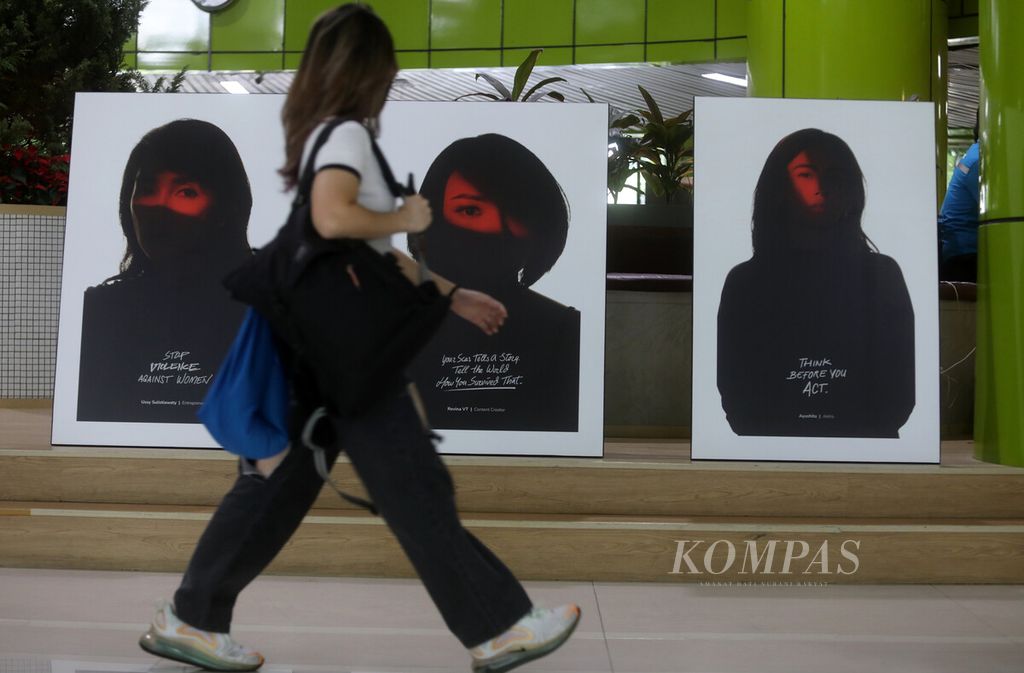 Calon penumpang melintas di depan foto-foto aktivis perempuan yang menyuarakan kampanye antikekerasan terhadap perempuan di Stasiun Gambir, Jakarta, Senin (12/12/2022). 