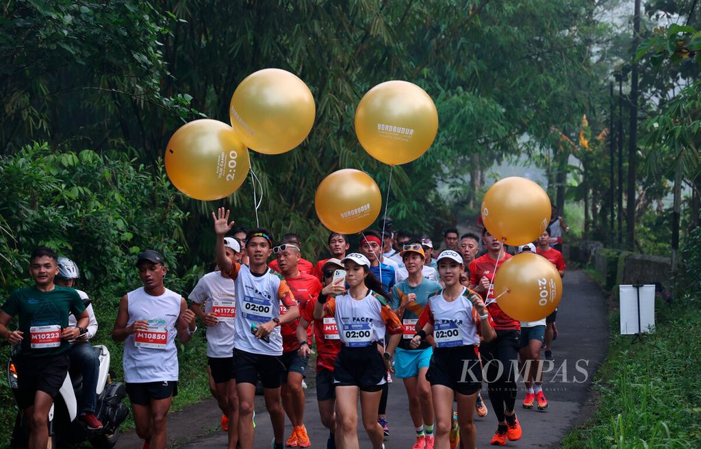 Tim pemandu mengaitkan balon sebagai penanda untuk menjaga ritme dan kecepatan lari bagi peserta lari Tilik Candi saat mengikuti Borobudur Marathon 2022 Powered by Bank Jateng di kawasan Candi Borobudur, Jawa Tengah, Minggu (13/11/2022).