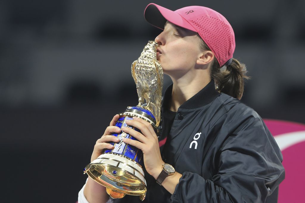 Petenis Polandia, Iga Swiatek, mencium trofi sebagai juara WTA 1000 Doha setelah mengalahkan Elena Rybakina (Kazakhstan) di Khalifa International Tennis Squash Complex, Doha, Qatar, Sabtu (17/2/2024) malam waktu setempat. Swiatek menang, 7-6 (8), 6-2. 