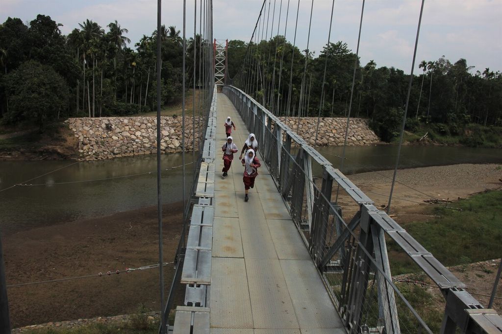 Siswa melintasi jembatan gantung di Desa Siron, Kecamatan Cot Glie, Kabupaten Aceh Besar, Provinsi Aceh, Kamis (16/3/2023). Setelah terisolasi karena jembatan lama ambruk diterjang banjir, kini kehadiran jembatan tersebut seperti impian warga yang terwujud. Pembangunan jembatan itu dibiayai oleh APBN sebesar Rp 4,4 miliar tahun 2022.