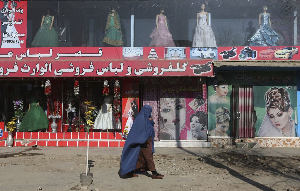 Seorang perempuan berjalan melewati salon kecantikan dan toko pakaian di Kabul, Afghanistan, Minggu, 13 Desember 2015. Juru bicara Kementerian Wakil dan Kebajikan Afghanistan mengatakan Selasa, 4 Juli 2023, Taliban melarang salon kecantikan perempuan. 