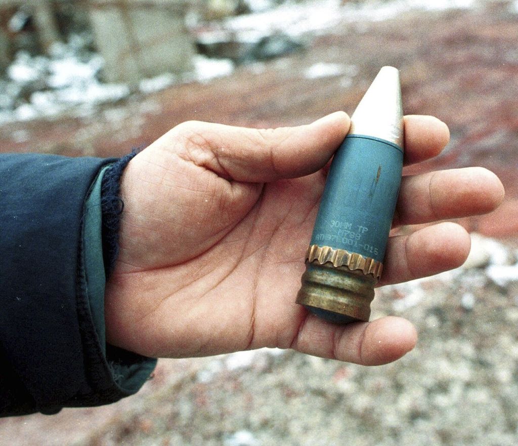 Anggota tim penanggulangan radioaktif memegang peluru penembus lapis baja mengandung uranium habis berukuran 30 mm yang digunakan NATO pada serangan di Bosnia pada 1995. Peluru itu ditemukan di bekas pabrik militer di daerah sub-urban Vogosca, dekat Sarajevo, 15 Januari 2001. 