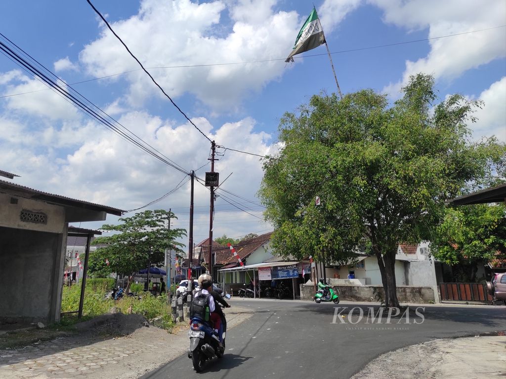 Sebuah motor melalui sebuah pohon yang terdapat bendera pendukung PS Sleman di Jalan Anggrek Sambilegi Lor, Maguwoharjo, Kabupaten Sleman, Selasa (9/8/2022). Pendukung PSS umumnya memasang bendera berwarna hijau-putih-hitam atau hijau-putih-hijau.