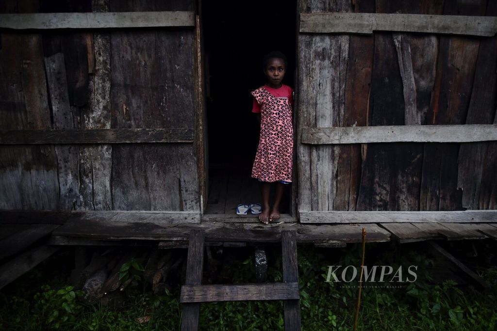 Seorang anak perempuan berdiri di depan pintu rumahnya di Kampung Kwau, Distrik Warmare, Kabupaten Manokwari, Papua Barat, setelah hujan turun, Selasa (13/4/2021). 