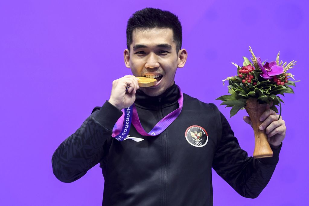 Pewushu Indonesia, Harris Horatius, menggigit medali emas seusai final nomor <i>nangun</i> putra Asian Games 2022 di Xiaoshan Guali Sports Centre, Hangzhou, China, Selasa (26/9/2023). Harris berhasil meraih emas seusai meraih total poin 19,506 (<i>nanquan</i> 9,756 poin dan <i>nangun</i> 9,750 poin).