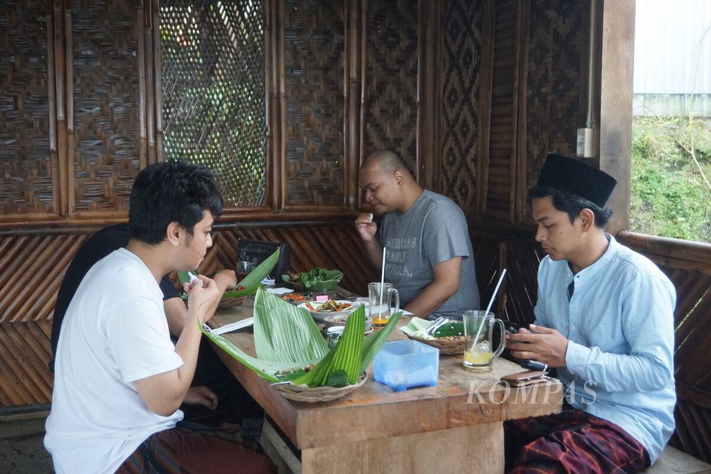 Hasan (27) dan teman-temannya dari Yogyakarta menikmati sega nyangku di Oemah Nyangku, Karangsalam, Baturraden, Banyumas, Jawa Tengah, Sabtu (1/10/2022).