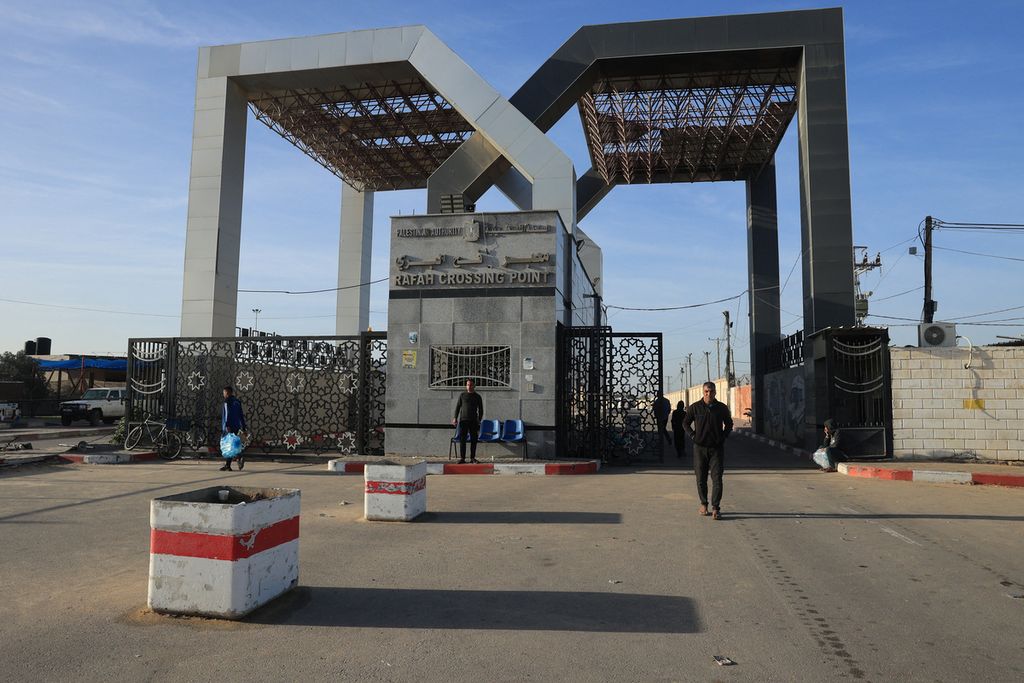Orang-orang berdiri di depan gerbang penyeberangan Rafah di sisi Palestina selama jam-jam pertama gencatan senjata empat hari antara Israel dan militan Hamas, Jumat (24/11/2023). Sandera yang diambil Hamas dilaporkan akan menyeberang ke Mesir kemudian diterbangkan ke Israel. 