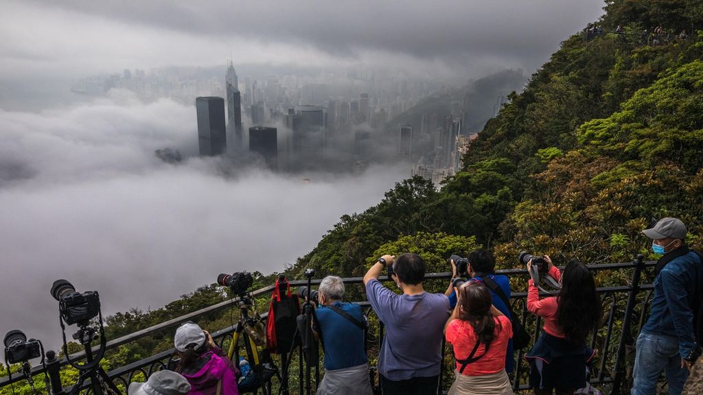 Warga mengabadikan pemandangan Hong Kong yang berselimut kabut tebal dari sebuah bukit, Selasa (22/3/2022). Di media sosial seperti Youtube, warga juga berbagi video mengenai fenomena ini. 