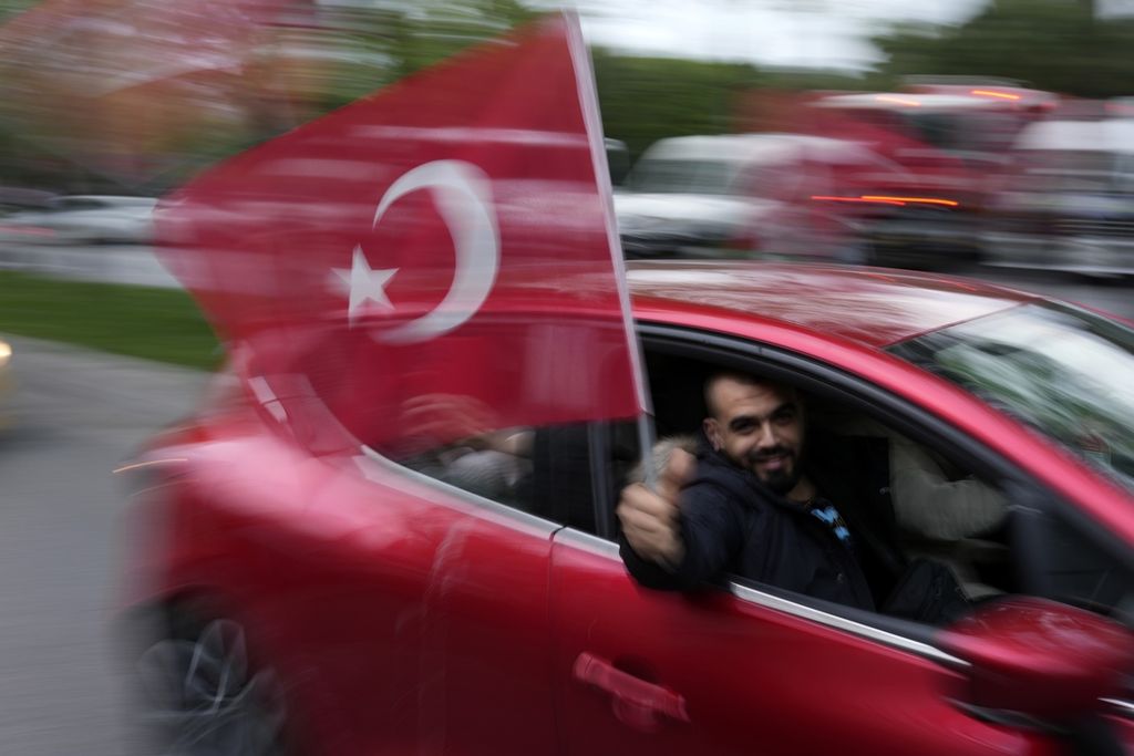 Seorang pendukung petahana Presiden Recep Tayyip Erdogan mengibarkan bendera Turki, merayakan keunggulan calon pilihannya berdasarkan penghitungan suara sementara pemilu Turki 2023 di Istanbul, Turki, Minggu (14/5/2023). Hasil penghitungan suara sementara, Killicdaroglu dan rivalnya Recep Tayyip Erdogan tidak memenuhi syarat mendapat dukungan 50 persen dan harus bertarung pada pemungutan suara putaran ke dua, 28 Mei nanti. (AP Photo/Francisco Seco)