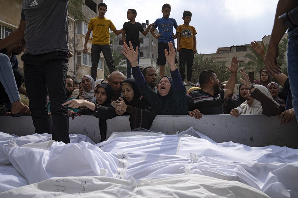Kerabat berduka atas korban tewas dalam serangan udara Israel di kota Gaza, Senin (9/10/2023). 