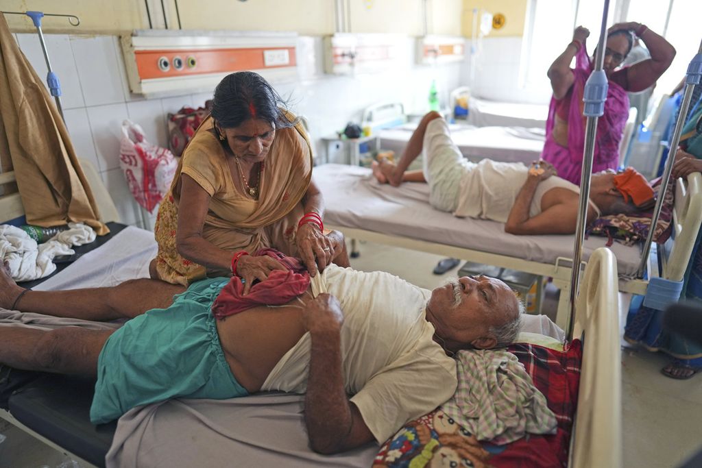 Seorang perempuan mengusap tubuh suaminya dengan baju dingin untuk menjaga tubuh suaminya tidak kepanasan di sebuah rumah sakit pemerintah daerah di Ballia, Negara Bagian Uttar Pradesh, India, 19 Juni 2023. 
