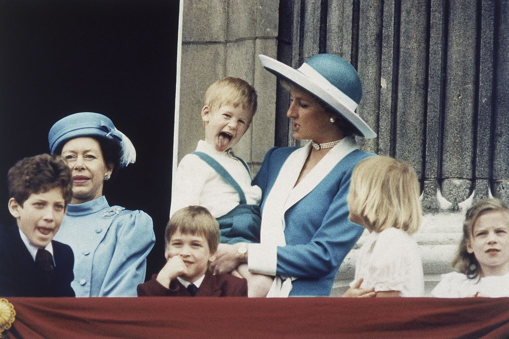 Dalam gendongan ibunya, Putri Diana, Pangeran Harry menjulurkan lidah ke arah kamera di balkon Istana Buckingham di London, Inggris, 11 Juni 1988. 