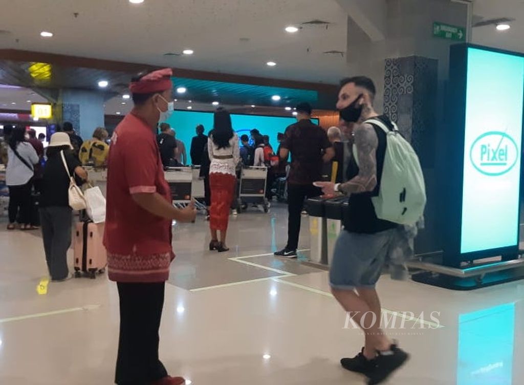 Turis meninggalkan terminal kedatangan di Bandara Internasional I Gusti Ngurah Rai, Kuta, Badung, Bali, Sabtu (19/3/2022) malam. Turis lokal dan internasional kembali meramaikan bandara ini setelah Pemerintah Indonesia memberikan pelonggaran aturan perjalanan awal Maret 2022.