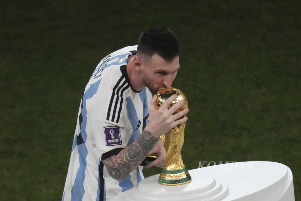 Pemain Argentina Lionel Messi mencium trofi Piala Dunia yang dimenangi Argentina pada partai final Piala Dunia 2022 di Stadion Lusail, Qatar, Senin (19/12/2022) dini hari WIB. Argentina menjuarai Piala Dunia 2022 setelah mengalahkan Perancis lewat adu tendangan penalti 7-5 (3-3).