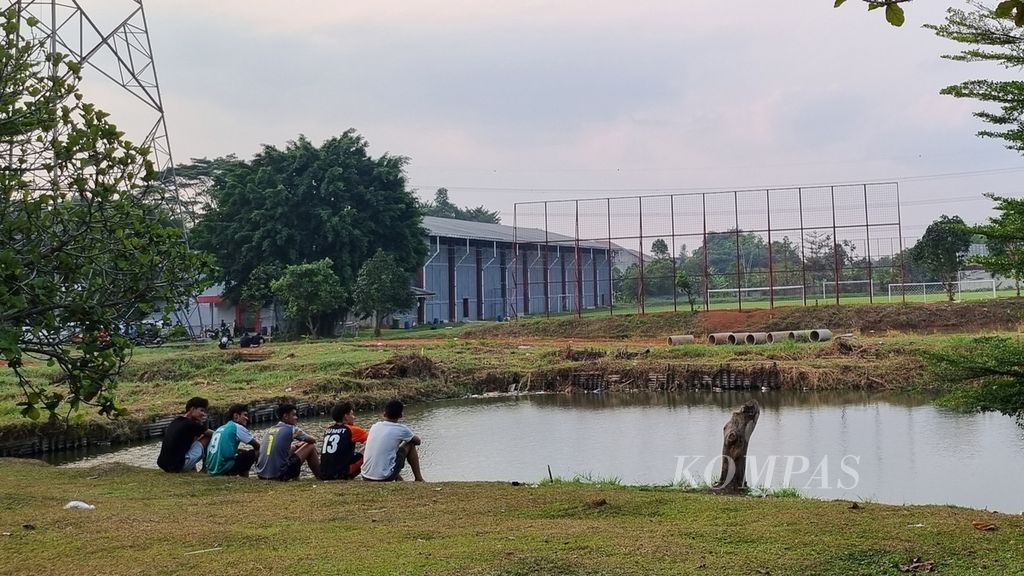 Sejumlah remaja tengah duduk menikmati sore dengan menghadapi lapangan latihan tim utama Persija Jakarta di Persija Development Center di Bojongsari, Depok, Jawa Barat, Selasa (8/8/2023). Persija memiliki lima lapangan di kompleks klub itu.