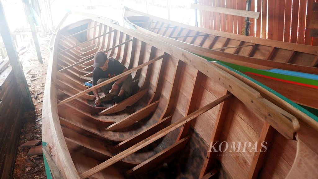 Seorang tukang membersihkan lambung perahu dalam proses akhir pembuatan perahu di Desa Pulau Sewangi, Kecamatan Alalak, Kabupaten Barito Kuala, Kalimantan Selatan, Sabtu (9/3/2024). 