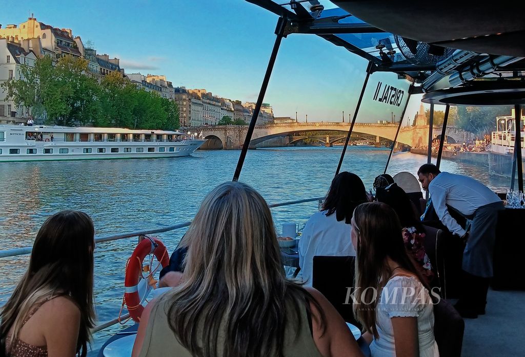 Para tamu menyusuri Sungai Seine dengan perahu wisata Bateau Parisien sembari menikmati senja kota Paris dan menyantap makanan, Selasa (18/7/2023). Di sepanjang Sungai Seine berjejer bangunan dan jembatan bersejarah.