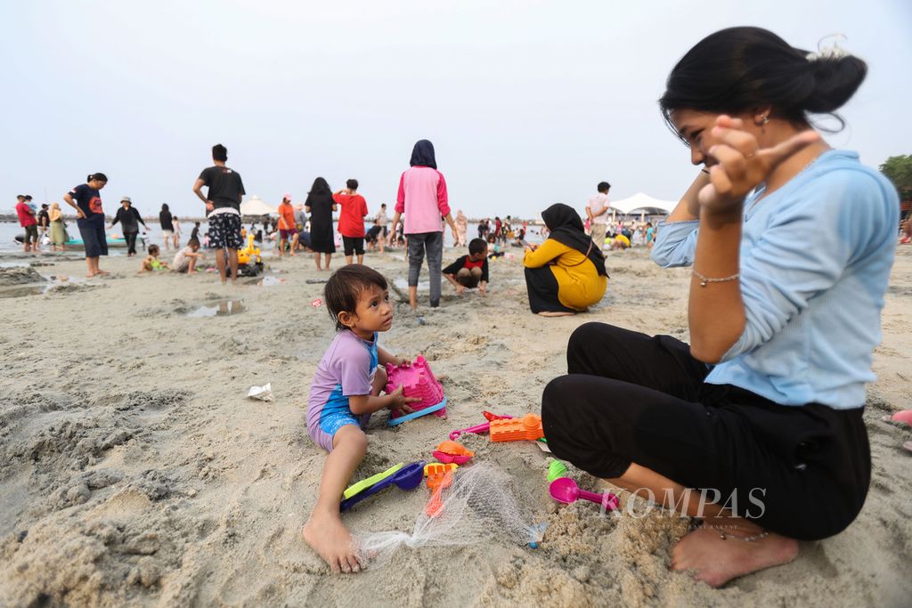 Seorang anak bermain pasir di Pantai Ancol, Jakarta, Senin (25/12/2023). Ancol Taman Impian masih menjadi salah satu destinasi wisata favorit warga saat libur Natal 2023 dan Tahun Baru 2024.  