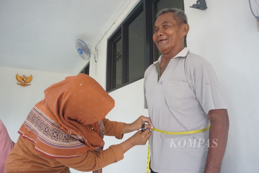 Seorang kader posyandu mengukur lingkar perut seorang warga lansia di Balai RW 003, Desa Karangrau, Kecamatan Sokaraja, Kabupaten Banyumas, Jawa Tengah, Sabtu (11/11/2023).