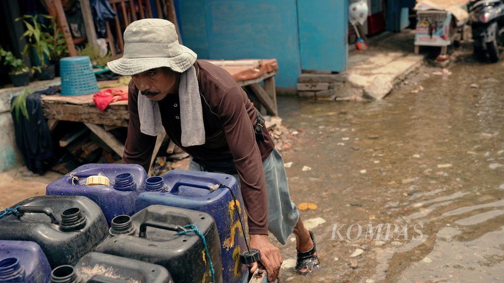 Penjual air bersih melintasi rob di RT 005 RW 002 Kelurahan Pluit, Penjaringan, Jakarta Utara, Kamis (6/1/2022).