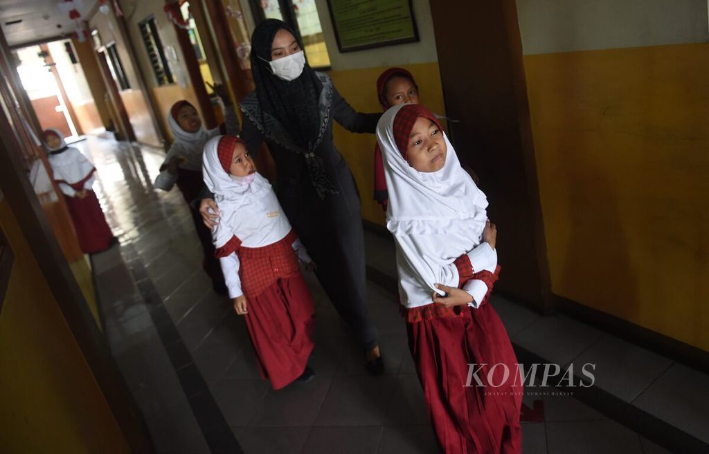 Siswa kelas I didampingi guru untuk menuju ruang imunisasi di Madrasah Ibtidaiyah Al Karim, Surabaya, Jawa Timur, Selasa (20/9/2022). 