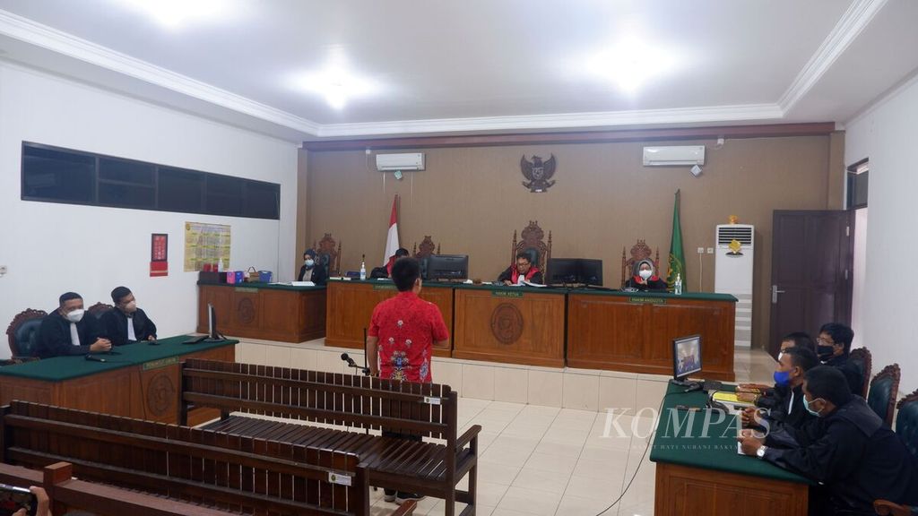 Kepala Desa Kinipan Willem Hengki (baju merah) berdiri saat mendengarkan amar putusan kasus dugaan korupsi yang menjeratnya di Pengadilan Tindak Pidana Korupsi Palangkaraya, Kalimantan Tengah, Rabu (15/6/2022). Willem terbukti tidak bersalah dan divonis bebas.