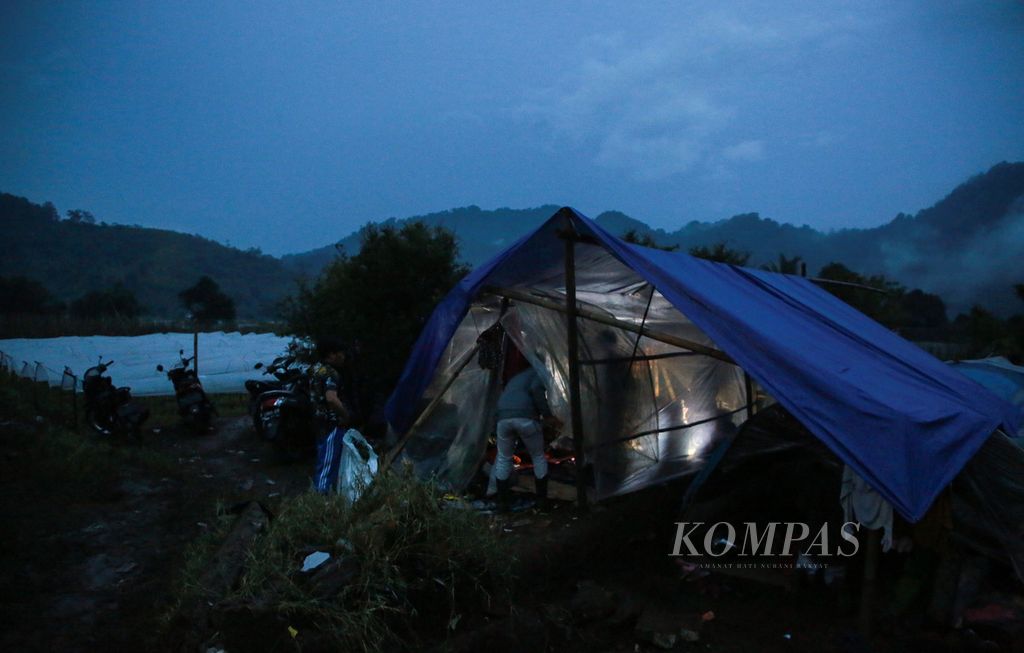 Relawan membagikan nasi bungkus untuk makan malam ke tenda-tenda pengungsi korban gempa bumi di area kebun sayur di Desa Ciputri, Kecamatan Pacet, Kabupaten Cianjur, Jawa Barat, Rabu (23/11/2022) malam.