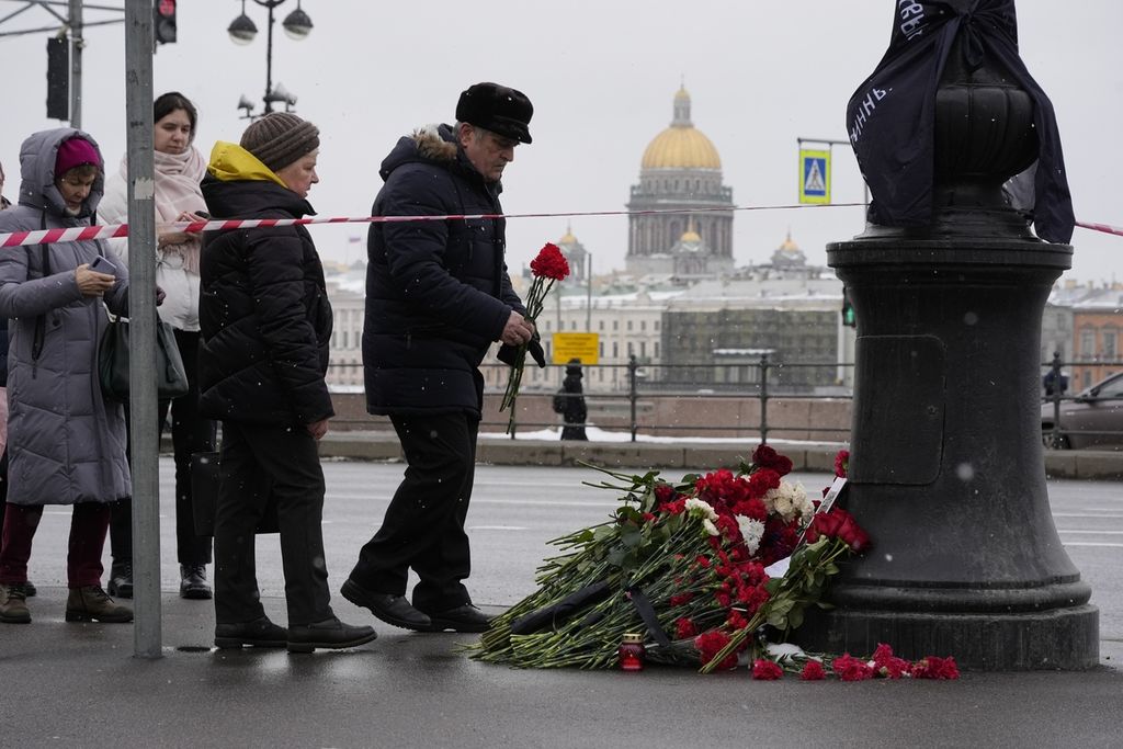 Sejumlah warga meletakkan karangan bunga di dekat lokasi ledakan bom di kafe "Street Bar" di St Petersburg, Rusia, Senin (3/4/2023).  (AP Photo/Dmitri Lovetsky)
