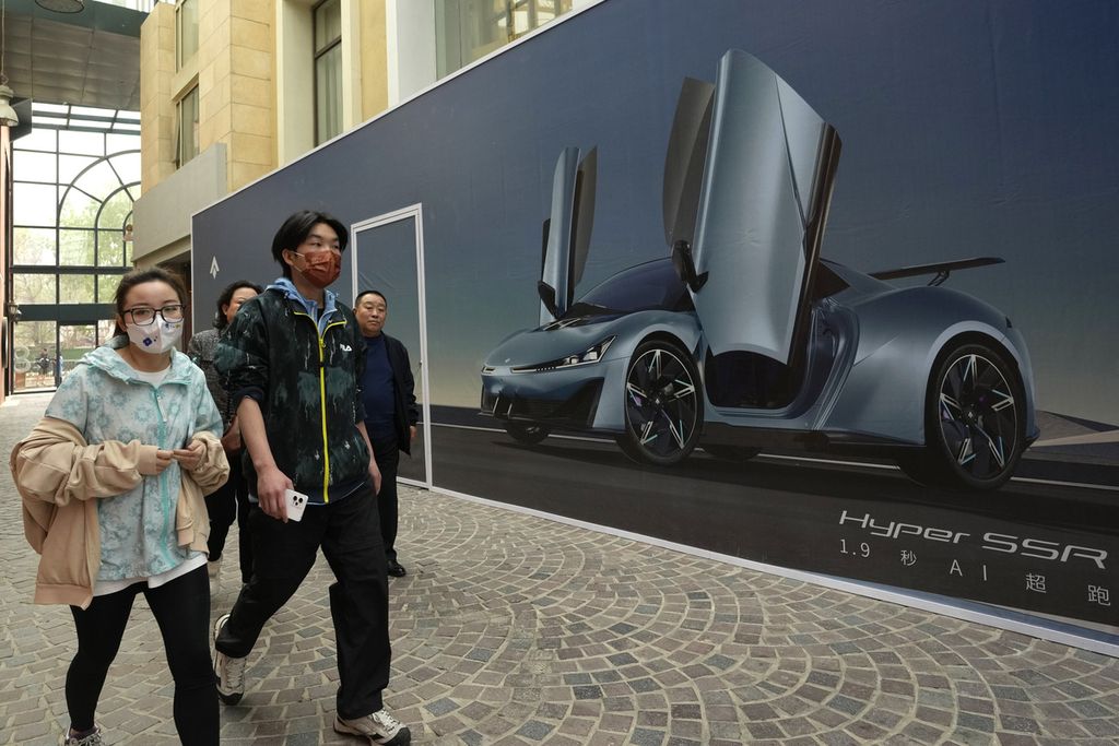 Warga berjalan di dekat iklan Hyper SSR sebuah mobil listrik dari pembuat mobil China GAC di Beijing, Kamis (13/4/2023). Pembuat mobil global dan China akan memamerkan puluhan SUV listrik baru dan sedan, serta supercar di pameran otomotif Shanghai. 
