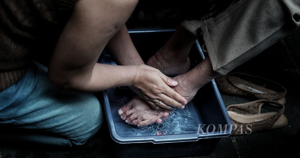 Seorang anak membasuhkan air ke kaki ibunya dalam kegiatan pencucian kaki ibu yang menjadi bagian rangkaian menjelang perayaan Cap Go Meh di Wihara Dhanagun (Hok Tek Bio), Kota Bogor, Jawa Barat, Sabtu (28/1/2023). 