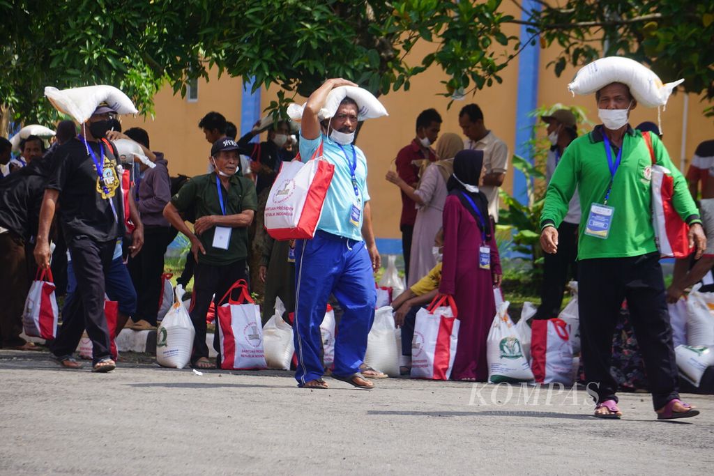 Presiden Joko Widodo mengecek penyaluran bantuan pangan di gudang Bulog, Klahang, Sokaraja, Banyumas, Jawa Tengah, Rabu (3/1/2024). Tampak warga penerima bantuan beras dan sembako membawa bantuan dari negara.