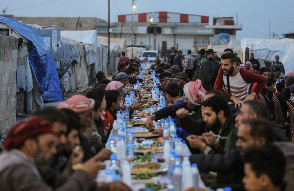 Pengungsi Suriah berbagi makanan saat berbuka puasa bersama di pengungsian yang berada dekat kota Al-Bab di utara provinsi Aleppo, Suriah, Kamis (7/4/2022).