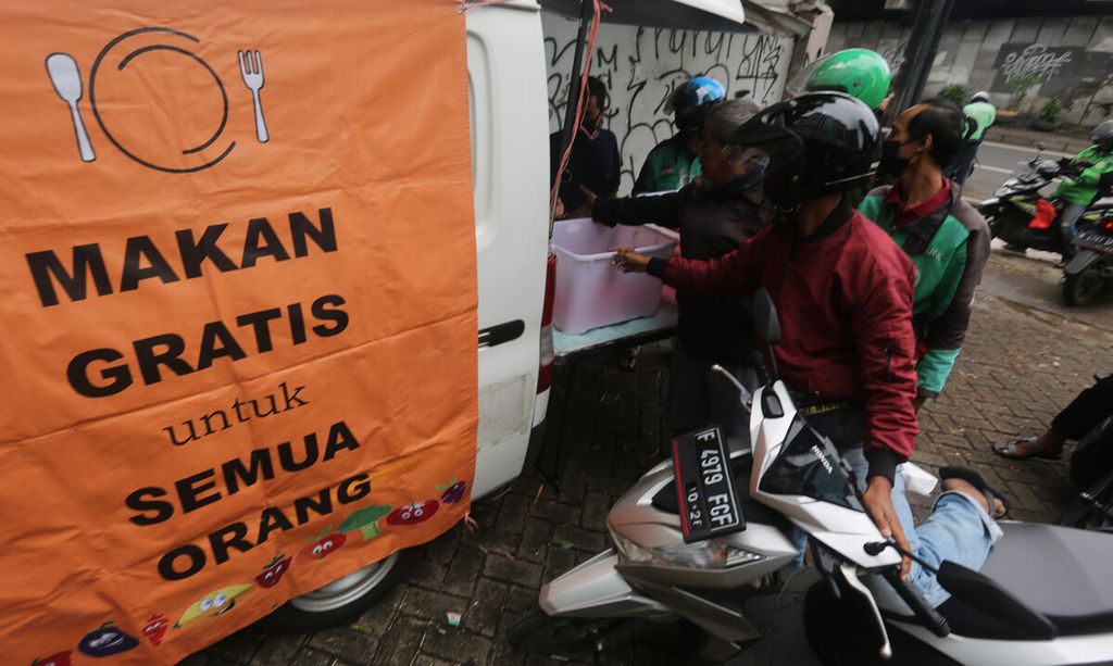 Warga menerima pembagian paket makan siang gratis dari sebuah mobil boks di kawasan Kampung Melayu, Jakarta Timur, Selasa (7/12/2021). Pembagian makna siang ini diperuntukkan bagi warga kurang mampu. Solidaritas sosial masih berkembang di tengah situasi pandemi yang meningkatkan angka kemiskinan di tengah masyarakat. 