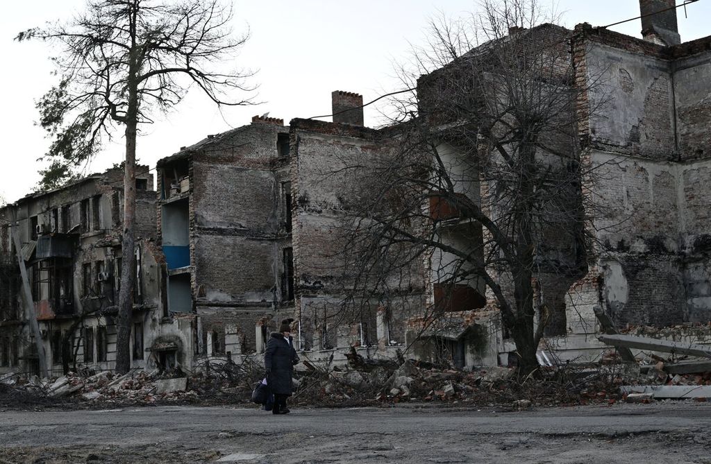 Seorang warga berjalan di depan apartemen yang rusak akibat perang di kota Lyman, Donetsk, Ukraina, 14 Desember 2022. 