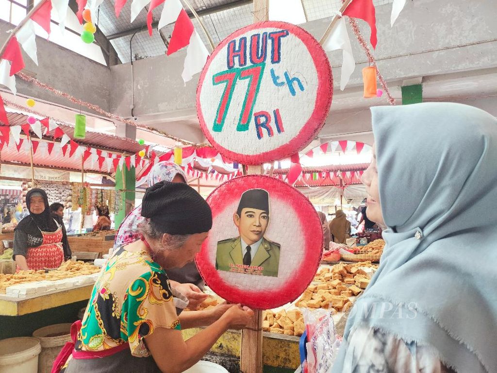Seorang pedagang tahu yang sudah lanjut usia memasang hiasan di tiang-tiang di mejanya di Pasar Rejowinangun, Kota Magelang, Jawa Tengah, Rabu (10/8/2022).