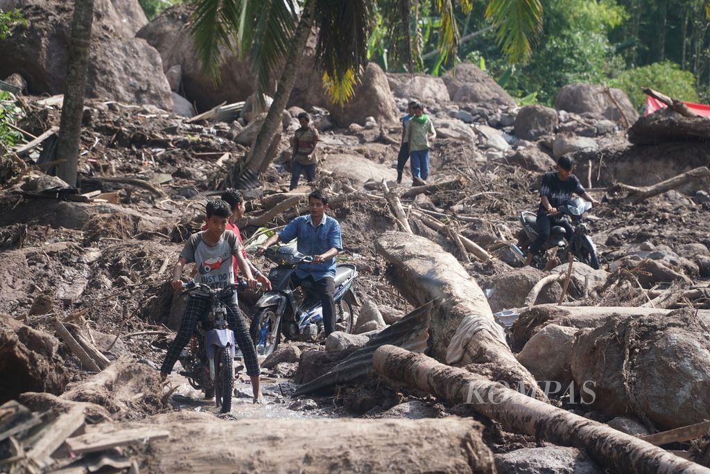 Warga melintas dengan sepeda motor di lokasi terparah banjir bandang di Kampung Langgai, Nagari Ganting Mudik Utara Surantih, Kecamatan Sutera, Kabupaten Pesisir Selatan, Sumatera Barat, Kamis (14/3/2024). 