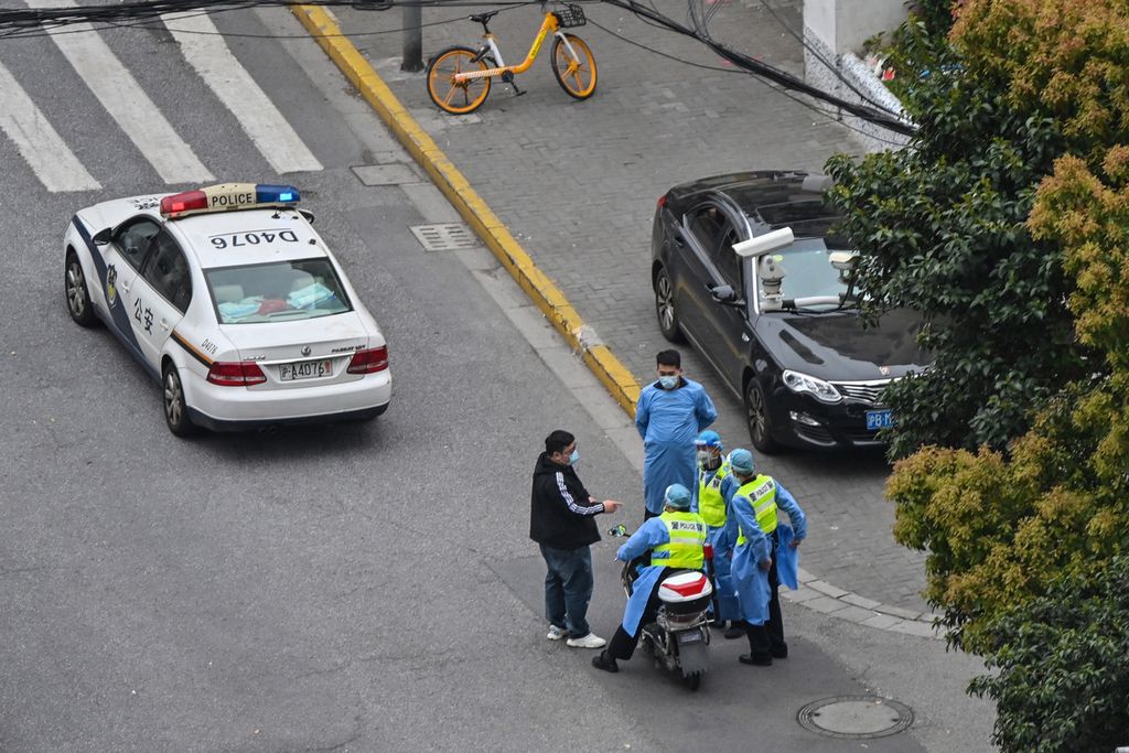Polisi mengenakan baju pelindung diri terlihat di sebuah ruas jalan di Distrik Jing'an, Shanghai, China, saat penguncian total wilayah atau <i>lockdown</i>, 5 April 2022, menyusul lonjakan kasus Covid-19.  