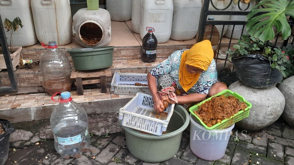 Siti Zulaikah (68), salah satu pegawai, memanen ekoenzim yang baru saja diambil dari jeriken berkapasitas 60 liter untuk selanjutnya diperas menggunakan kain, Rabu (29/11/2023), di Perumahan Puri Savira, Desa Mojorejo, Kecamatan Junrejo, Kota Batu, Jawa Timur.