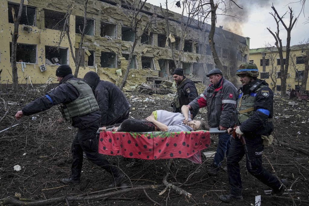 Pekerja dan relawan darurat Ukraina membawa seorang wanita hamil yang terluka dari rumah sakit bersalin yang rusak akibat penembakan di Mariupol, Ukraina, Rabu, (9/3/2022). Rumah sakit ibu dan anak itu hancur setelah dibom Rusia.