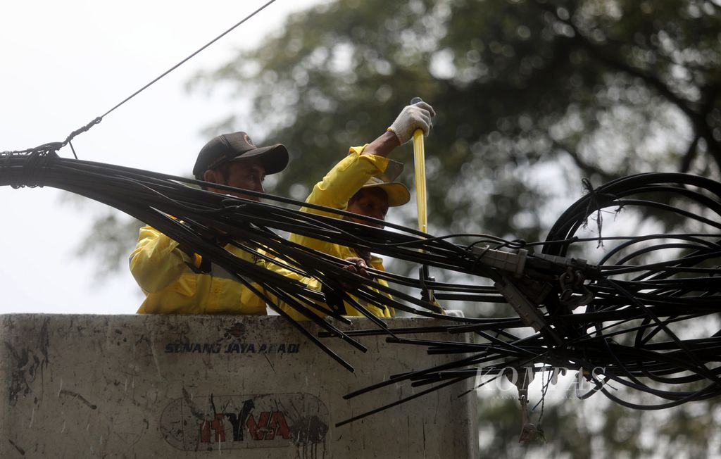 Petugas Dinas Bina Marga memotong kabel utilitas yang dibersihkan dari tiang-tiang di kawasan Jalan Jenderal Sudirman, Jakarta Selatan, Selasa (9/5/2023). Penertiban jaringan utilitas berupa pemutusan kabel dan pencabutan tiang sepanjang 700 meter di kawasan Sudirman itu dilakukan dalam rangka jelang penyelenggaraan KTT ASEAN 2023 di Jakarta pada bulan September. 