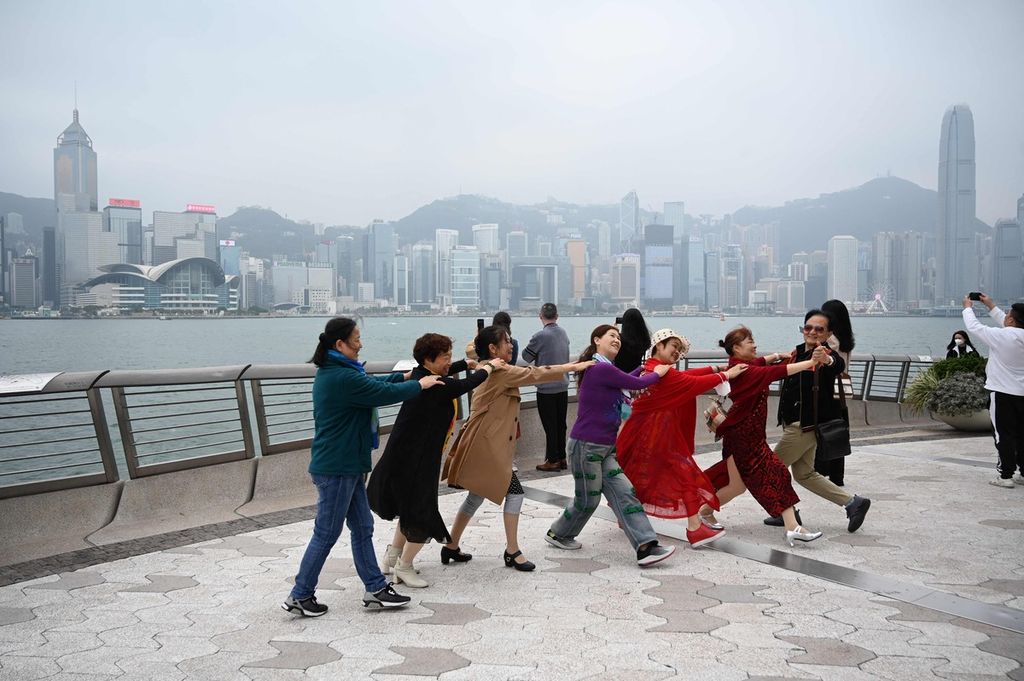 Para turis dari China daratan menari di dermaga di Hong Kong, Senin (13/3/2023). 