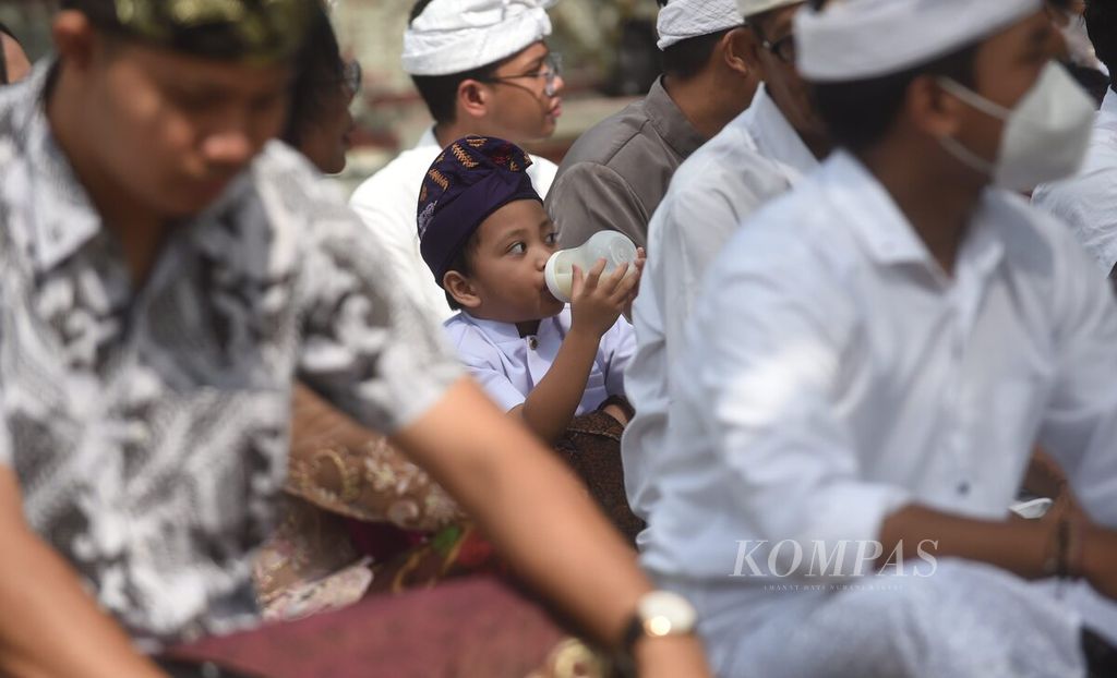 Seorang anak minum susu saat akan sembahyang hari raya Galungan di Pura Sagara Kenjeran, Surabaya, Jawa Timur, Rabu (4/1/2022). 