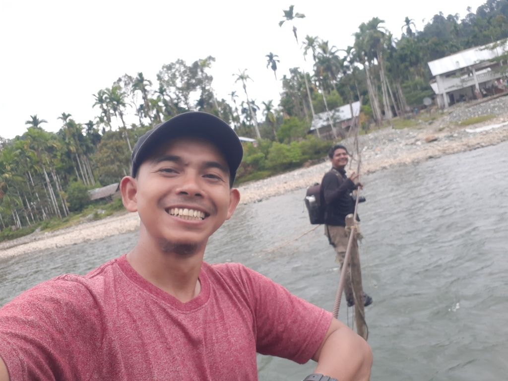 Penulis (kaus merah) saat meniti jembatan kabel di Desa Sikundo, Kecamatan Pante Ceureumen, Kabupaten Aceh Barat, Provinsi Aceh, pada 22 Juli 2022.